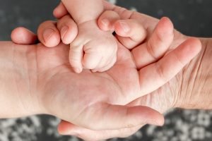 Infant's hand in mother and father's hands. 