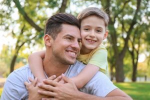 Son and father spending time together sitting in the grass