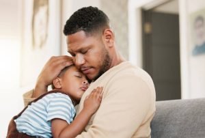 Father and daughter are both very sad and sitting on a couch. 